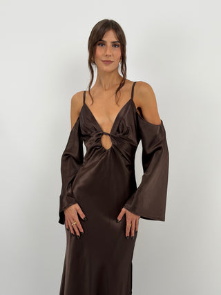 Abito lungo marrone in tessuto satinato fluido, con top a triangolo con cut out e arricciature. Spalline sottili, spalle scoperte e maniche lunghe. Zip laterale e spacco laterale.