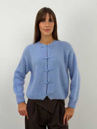 Cardigan azzurro polvere con alamari in stile orientale, in tessuto morbido misto mohair. Girocollo con finiture a costine.