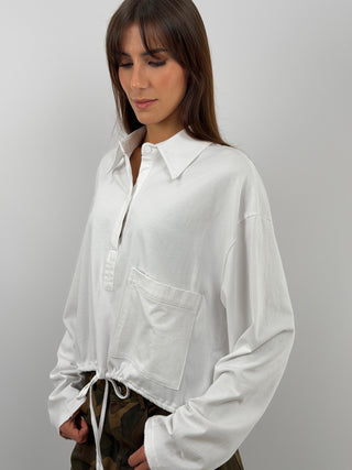 Maglia bianca a maniche lunghe con colletto e bottoni. Fit oversize con coulisse regolabile sul fondo e tasca frontale.