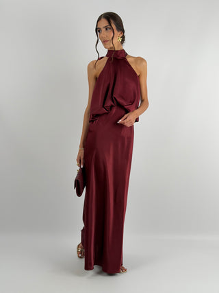 Abito burgundy in tessuto satinato con collo halter e top con balza arricciata. Spalline sottili e regolabili.