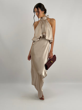 Abito champagne in tessuto satinato con collo halter e top con balza arricciata. Spalline sottili e regolabili.