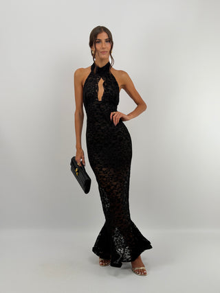 Abito in Pizzo Nero con Volant - Abito lungo nero aderente in pizzo, con collo halter e bottoncini sul retro. Cut out frontale a goccia, gonna aderente con volant ampio sul fondo, schiena scoperta. | Paloma Store