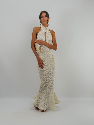 Abito in Pizzo Panna con Volant - Abito lungo panna aderente in pizzo, con collo halter e bottoncini sul retro. Cut out frontale a goccia, gonna aderente con volant ampio sul fondo, schiena scoperta. | Paloma Store