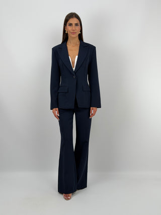 Completo Giacca Monopetto e Pantalone Blu - Completo blu, composto da giacca monopetto sfiancata con rever e fodera interna, e pantalone flare con elastico in vita sul retro, chiusura con zip e bottone e tasche laterali. | Paloma Store