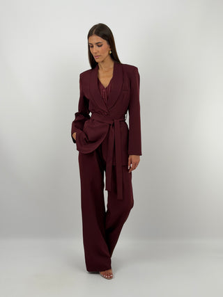 Completo Blazer con Cintura e Pantalone Bordeaux - Completo bordeaux, composto da blazer con cintura, collo a scialle e fodera interna, e pantalone a palazzo con tasche laterali, chiusura con zip e bottone ed elastico in vita sul retro. | Paloma Store