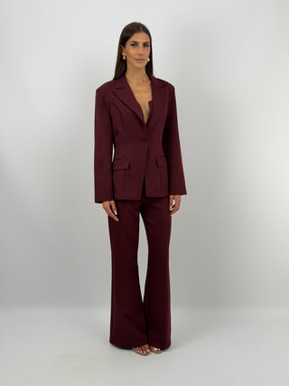 Completo Giacca Monopetto e Pantalone Bordeaux - Completo bordeaux, composto da giacca monopetto sfiancata con rever e fodera interna, e pantalone flare con elastico in vita sul retro, chiusura con zip e bottone e tasche laterali. | Paloma Store