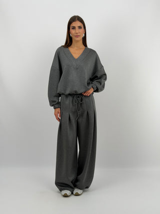 Completo Felpa e Pantalone Scollo V Grigio Lumina - Completo in felpa grigio composto da due pezzi. La felpa presenta maniche lunghe e scollo a V. Il pantalone sportivo ha coulisse sul fondo, lacci regolabili in vita e tasche laterali. | Paloma Store
