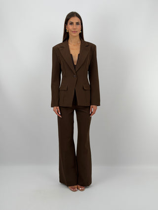 Completo Giacca Monopetto e Pantalone Marrone - Completo marrone, composto da giacca monopetto sfiancata con rever e fodera interna, e pantalone flare con elastico in vita sul retro, chiusura con zip e bottone e tasche laterali. | Paloma Store