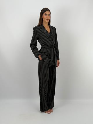 Completo Giacca con Cintura e Pantalone Gessato Nero - Completo nero in tessuto gessato, composto da blazer doppiopetto con cintura in vita e tasche con patta, e pantalone palazzo con elastico in vita, tasche laterali e chiusura con zip e bottone. Gilet abbinato acquistabile separatamente. | Paloma Store