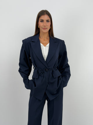 Tailleur con Spalle Strutturate Blu - Completo tailleur blu con blazer dalle spalle strutturate, maniche ampie, cinturina in vita e fodera interna. Pantalone a palazzo con passanti per cintura, chiusura con zip e bottone ed elastico in vita. | Paloma Store