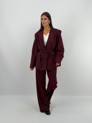 Tailleur con Spalle Strutturate Burgundy - Completo tailleur burgundy con blazer dalle spalle strutturate, maniche ampie, cinturina in vita e fodera interna. Pantalone a palazzo con passanti per cintura, chiusura con zip e bottone ed elastico in vita. | Paloma Store