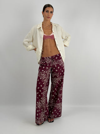 Pantalone Palazzo con Fantasia Bandana Burgundy - Pantalone lungo a palazzo in fantasia bandana a contrasto. Presenta laccio regolabile in vita, fodera interna, tasche laterali e tasca sul retro. | Paloma Store